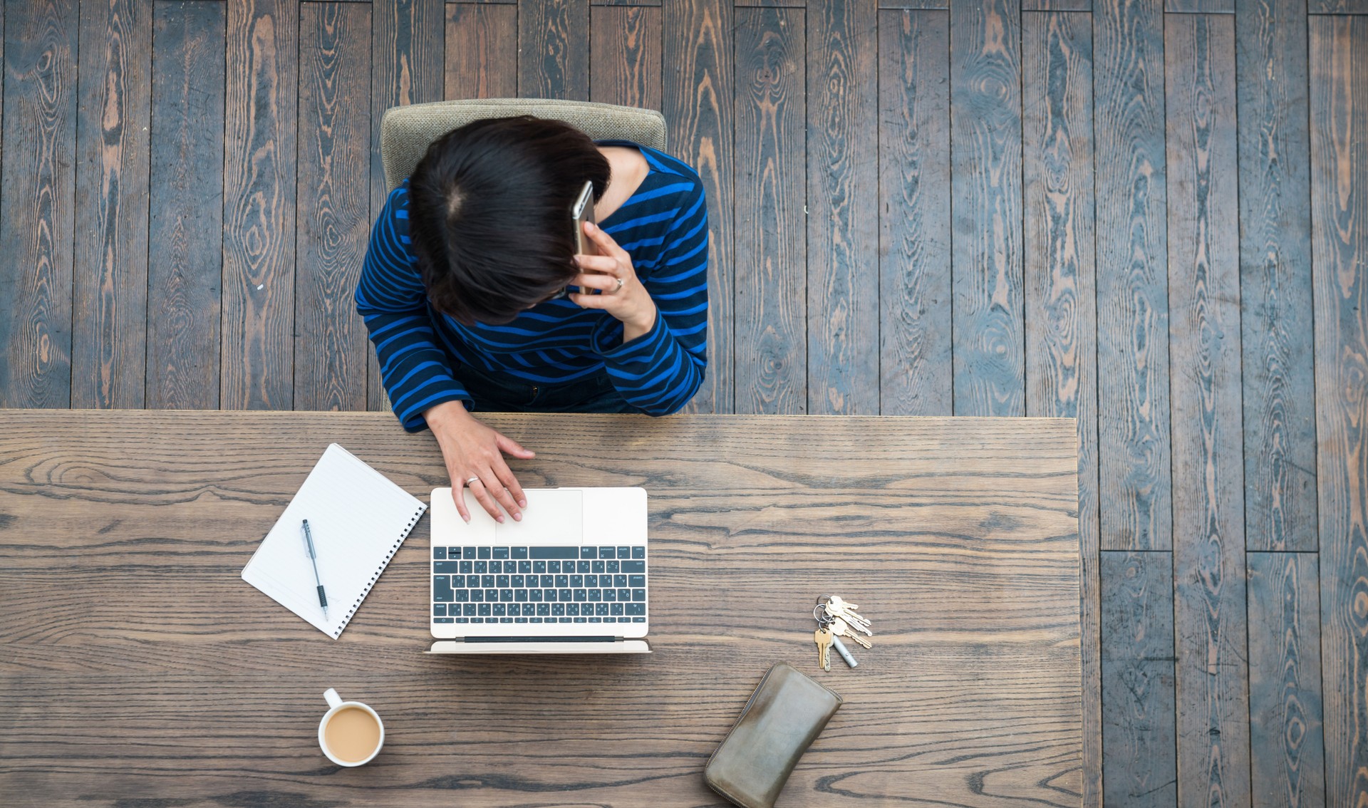 Woman talking on phone while using a laptop