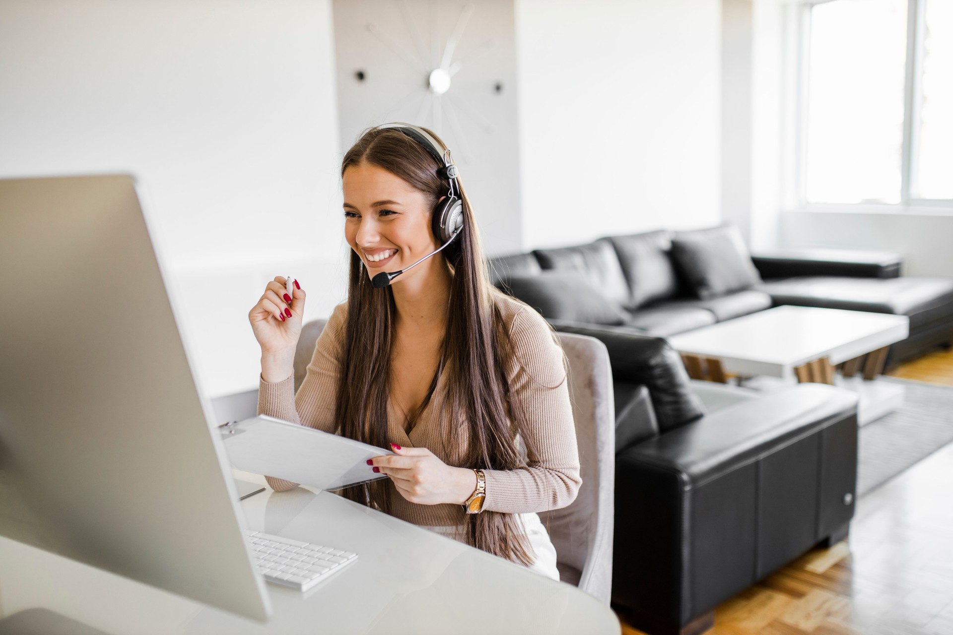 Happy woman with headset having video call and working on computer in her home office